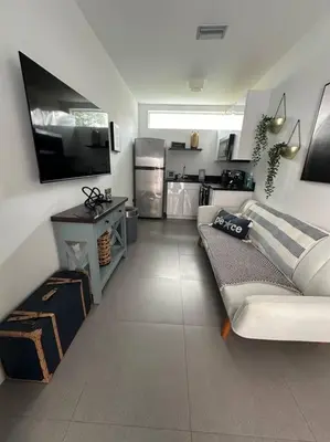 a living room with a white couch and a kitchen at Charming House at Miami's Heart in Miami