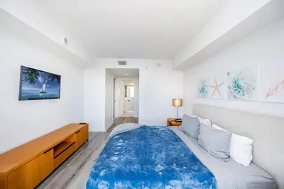 a white bedroom with a large bed with a blue blanket at Beachwalk - 1 Bedroom & Kitchen Amazing Bay view in Hallandale Beach