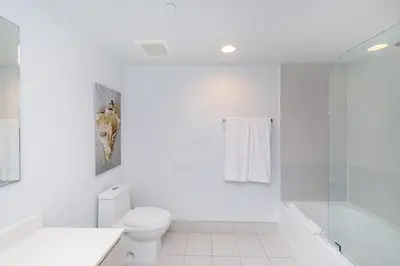 a white bathroom with a toilet and a shower at 2 Bed 2 Bath With Amazing Bay View And Luxury Pool in Hallandale Beach