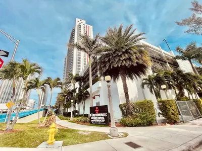 a building with palm trees and a yellow fire hydrant at 2 Bed 2 Bath With Amazing Bay View And Luxury Pool in Hallandale Beach