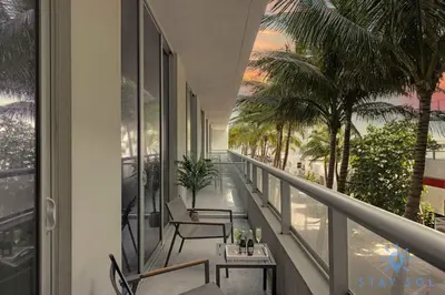 a balcony with chairs and tables and palm trees at Beautiful Apt 2BR Hollywood Beach Rooftop Pool in Hollywood