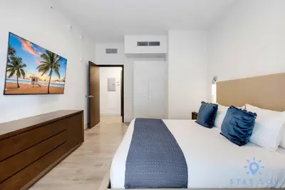 a bedroom with a large bed with blue pillows at Beautiful Apt 2BR Hollywood Beach Rooftop Pool in Hollywood