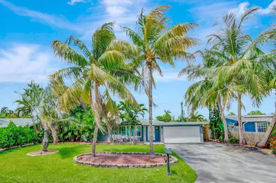 a house with palm trees in front of a driveway at Fort Lauderdale Tropical Oasis Pool Retreat in Fort Lauderdale