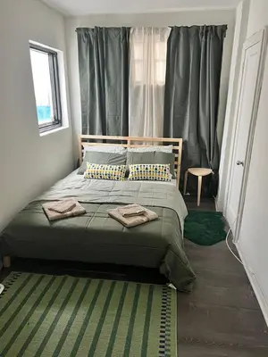 a bedroom with a bed with green sheets and a window at Villa Jazmin Beach in Miami Beach