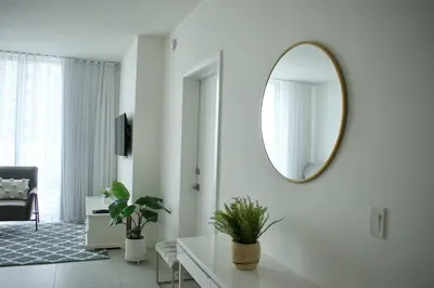 a white living room with a mirror on the wall at Luxury apartment in Doral miami, 1 Bd in Miami