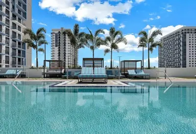 a swimming pool with chairs and palm trees in a building at Luxury apartment in Doral miami, 1 Bd in Miami