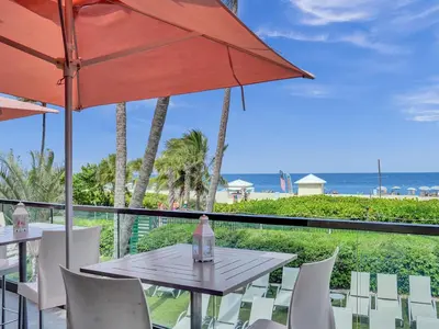 a table and chairs with an umbrella and the beach at Adorable 2 Bedroom Condo Beach Service 1110 in Miami Beach