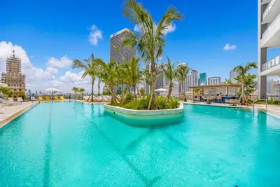 a large swimming pool with palm trees in a city at Upscale 1-BD Condo with Stunning City Views in Miami