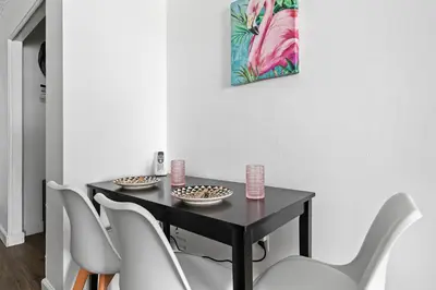 a dining room table with white chairs and a painting at Palms 811 in Miami Beach