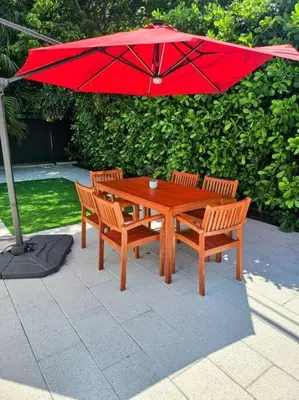 a wooden table with two chairs and a red umbrella at Brickell Enclave Sunny Retreat with pool in Miami