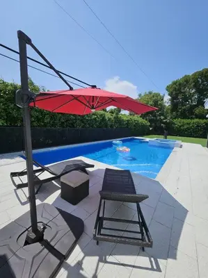 a red umbrella and a chair next to a swimming pool at Brickell Enclave Sunny Retreat with pool in Miami