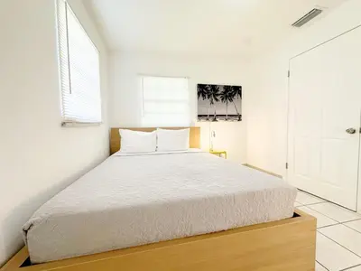 a bedroom with a large bed with white sheets at Modern Miami Family Cottage Beach 15 min in Miami