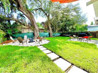 a backyard with chairs and tables and a tree at Modern Miami Family Cottage Beach 15 min in Miami