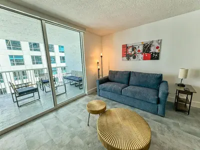 a living room with a blue couch and a large window at Elegant Centric Vibrant Pool Jacuzzi Free Parking in Miami