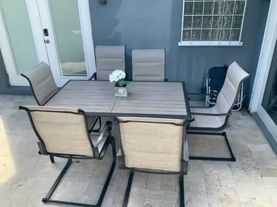 a wooden table and chairs with a table and flowers at POOLSIDE MANOR - Men Only Clothing-Optional in Fort Lauderdale