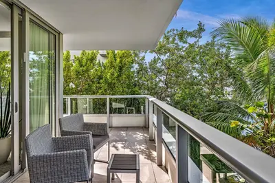 a balcony with two chairs and a table at Grand Deluxe Two Bedroom Suite with Balcony Water Views, Corner in Miami Beach