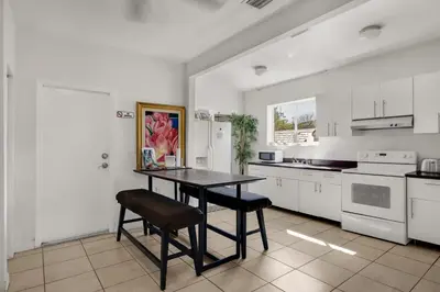 a kitchen with white cabinets and a table and chairs at Private Rooms at Miami, Buena Vista with Parking in Miami