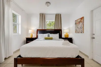 a bedroom with a large bed with two windows at Private Rooms at Miami, Buena Vista with Parking in Miami