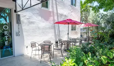 a patio with chairs and tables with umbrellas at 7130 Costa Boutique in Miami Beach