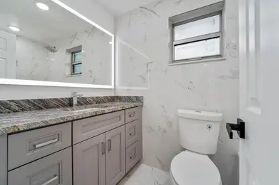 a bathroom with a toilet and a sink and a mirror at Miami Oasis Near Beach in North Miami