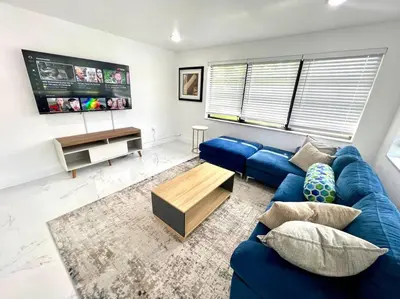 a living room with a blue couch and a tv at Miami Oasis Near Beach in North Miami
