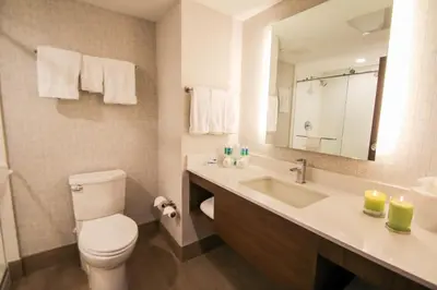 a bathroom with a toilet and a sink and a mirror at Holiday Inn Express & Suites Miami Airport East by IHG in Miami