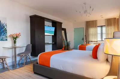 a hotel room with two beds and a flat screen tv at Seaside All Suites Hotel in Miami Beach