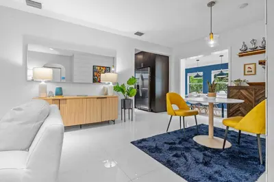 a living room and a kitchen with a table and yellow chairs at ArtHaus- Fully Stocked Kitchen and Fenced Yard in Miami