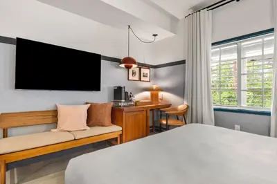 a bedroom with a bed and a desk and a tv at The Daydrift in Miami Beach