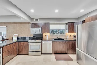 a kitchen with wooden cabinets and stainless steel appliances at Ft Lauderdale Casa de Las Olas in Fort Lauderdale