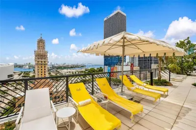 a balcony with yellow chairs and an umbrella at 2 bedroom Condo at Gale Downtown Pool Gym SPA in Miami