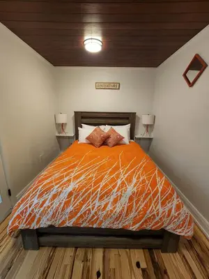 a bedroom with a bed with orange comforter and two lamps at Most Unique Space in Fort Lauderdale