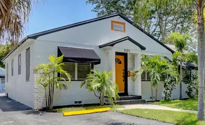 a white house with palm trees in front of it at Most Unique Space in Fort Lauderdale