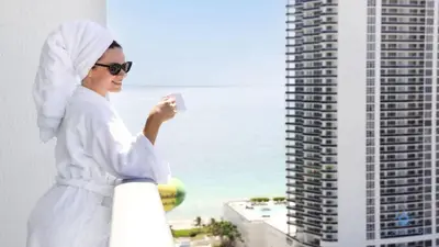 a woman in a white robe on a balcony with the ocean at Luxury Penthouse -Awesome Views-Pools - Free Parking in Hollywood