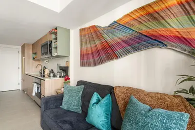 a living room with a couch and a colorful blanket hanging on the wall at Miami Luxury 27th Floor, Best Waterfront Balcony View & City Lights, Pool,Gym,Spa in Miami