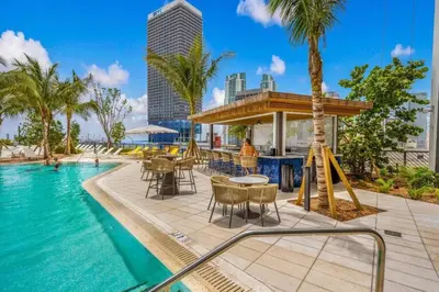 a pool at a resort with tables and chairs at Miami Luxury 27th Floor, Best Waterfront Balcony View & City Lights, Pool,Gym,Spa in Miami