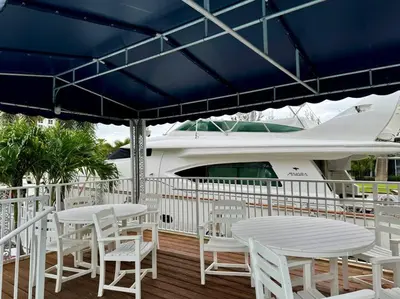 a deck with white tables and chairs and a boat at 1 Block from the Beach 2BR 2BA Newly Renovated in Fort Lauderdale