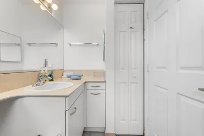 a white bathroom with a sink and a mirror at Bayside Townhome - Private Beach Access, Pool and Hot Tub, Free Parking in Golden Isles
