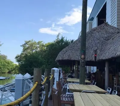 a restaurant with tables and chairs and a straw roof at Coastal Haven 5 Min to Beach, Patio, BBQ in Dania Beach