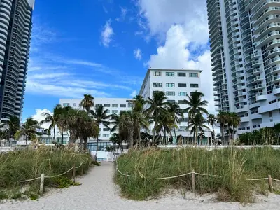 a beach with palm trees in front of a building at Casablanca miami beach in Miami Beach