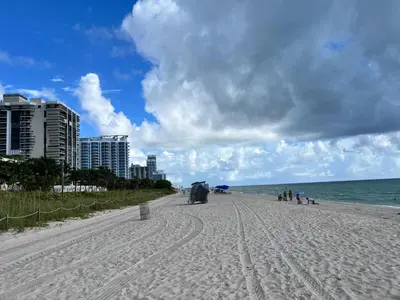 a beach with people sitting on the sand and the ocean at Casablanca miami beach in Miami Beach