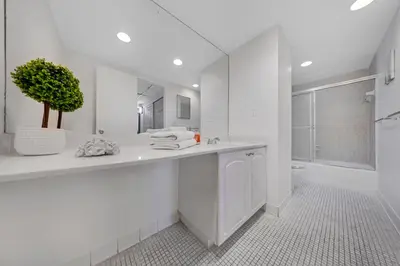 a white bathroom with a sink and a potted plant at Oceanfront Luxury Condo with Stunning Views and Resort Amenities in Hollywood