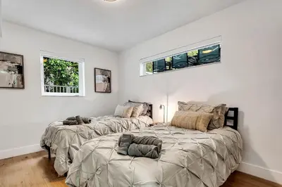 two beds in a white room with two windows at Villa Oasis with Heated Pool,Sauna, BBQ and Pool Table in Pinecrest