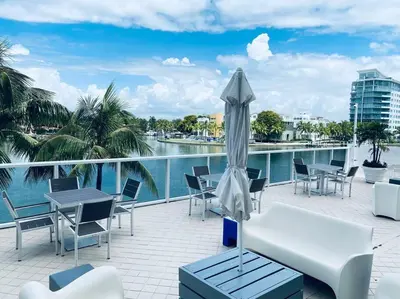 a patio with chairs and tables and an umbrella at OCEAN VIEW 1BR 2BA BEACH CONDO Parking in Miami Beach