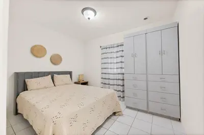 a white bedroom with a bed and a dresser at Beach Home Estate I Pool & Ocean in Fort Lauderdale
