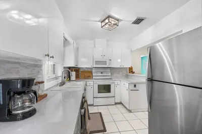 a kitchen with white cabinets and a stainless steel refrigerator at Beach Home Estate I Pool & Ocean in Fort Lauderdale