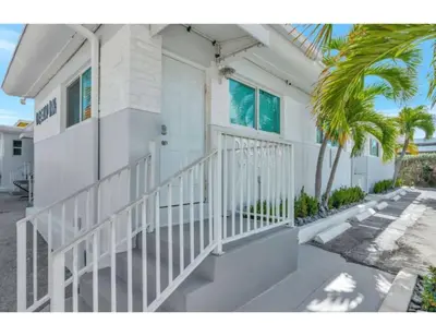 a white house with a white door and a palm tree at Sun kissed Charm Beachside Hollywood Studio in Hollywood