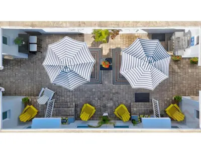 three umbrellas on a patio with chairs and tables at Coastal Comfort Hollywood Studio Retreat in Hollywood