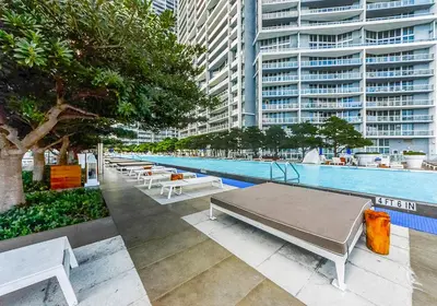a pool with tables and benches next to a building at Large Suites in Hotel W with bay views in Miami
