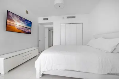 a white bedroom with a bed and a tv on the wall at Large Suites in Hotel W with bay views in Miami